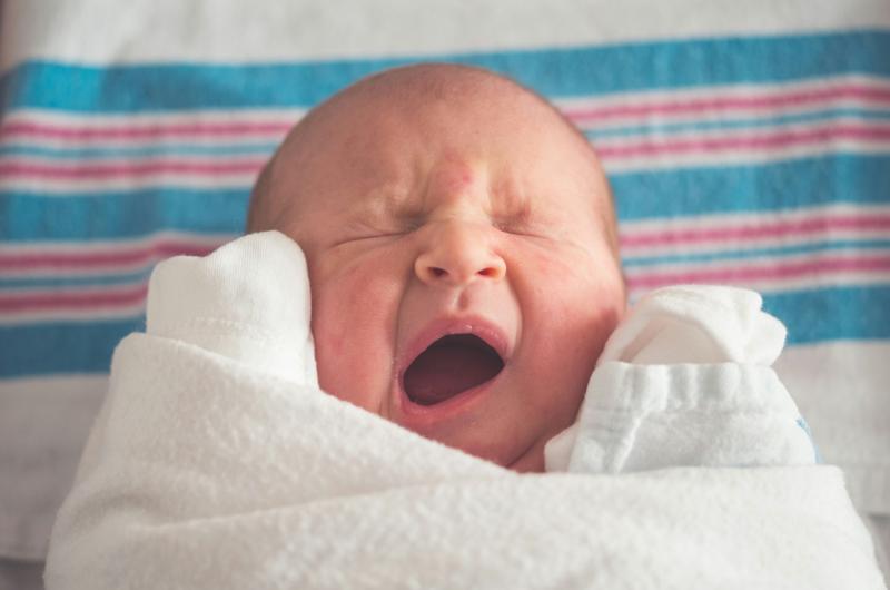 A baby yawning with its eyes closed